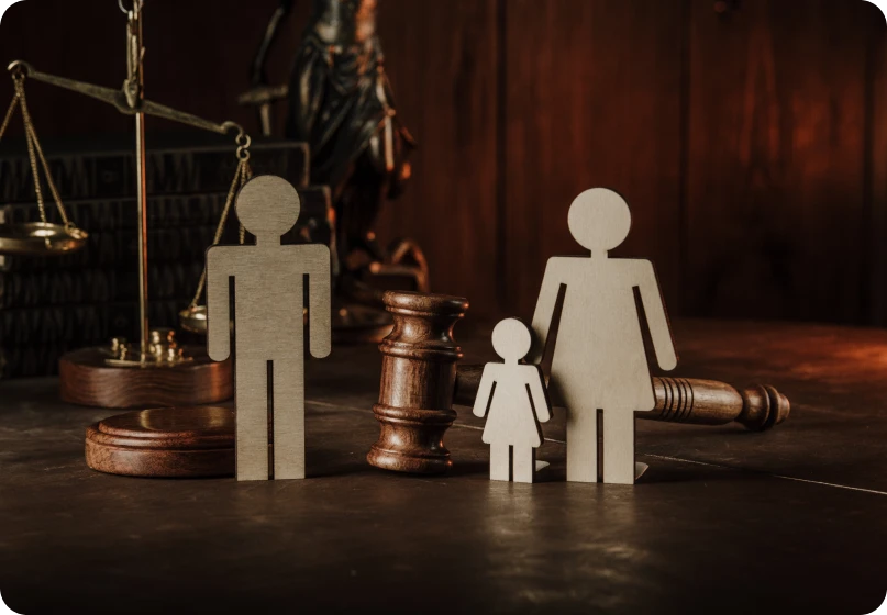 Family law enforcement concept with wooden figures of parents and child beside a judge’s gavel.