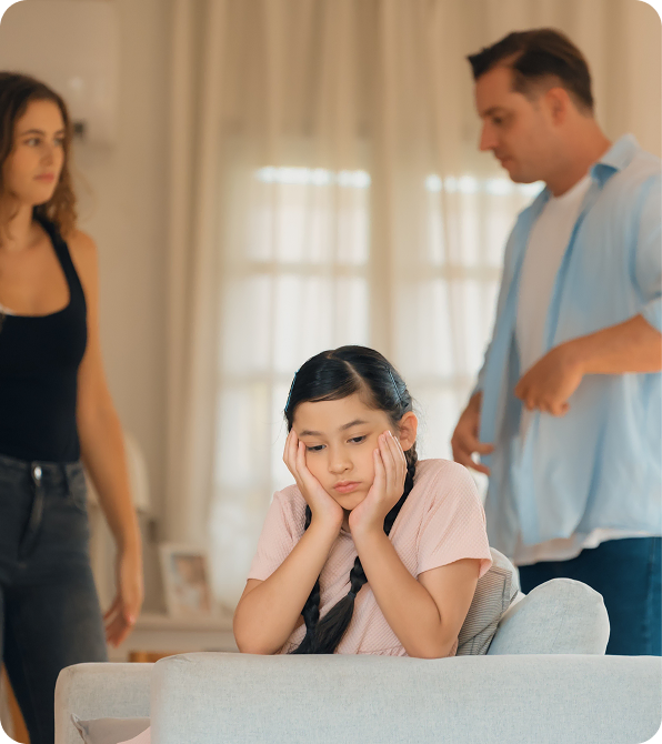 Child looking sad while parents argue during custody discussion.