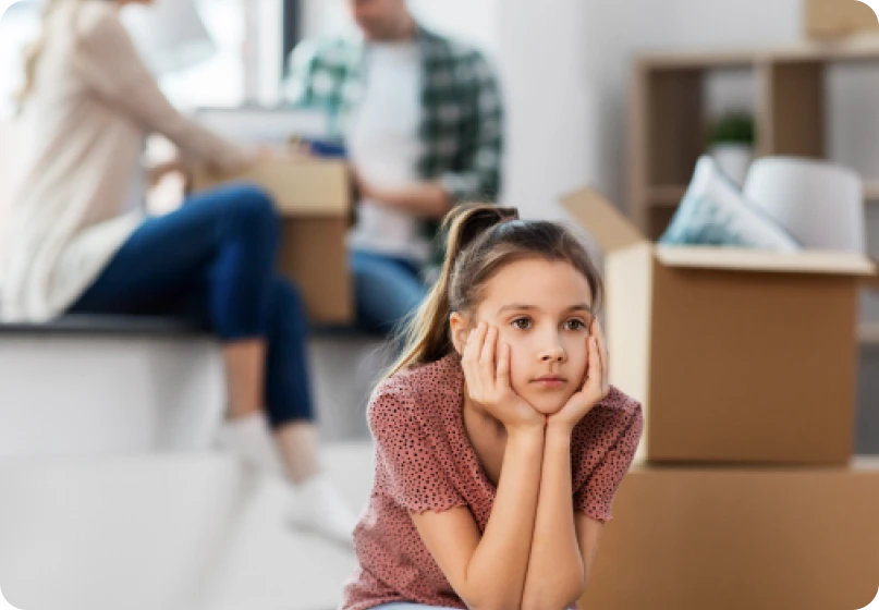 Child looking distressed as parents prepare to move out following a divorce.